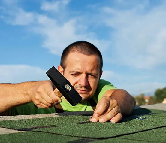 A man is holding a cell phone while laying on the roof.